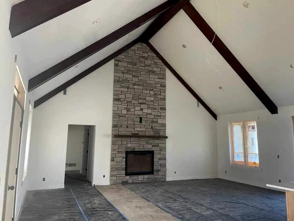 The same great room finished with paint, stone fireplace and exposed beams