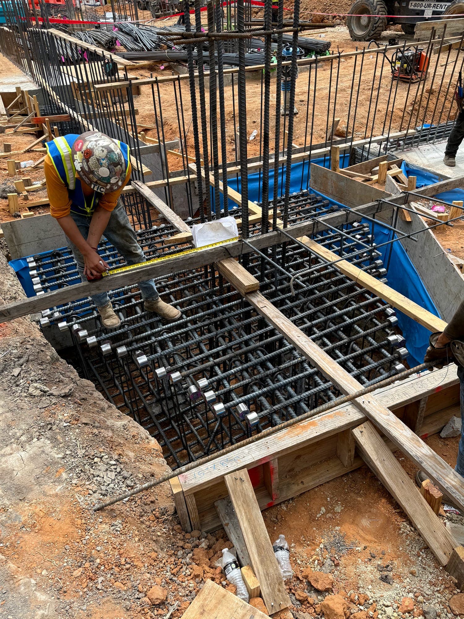 Worker tying reinforcing steel inside formed footings