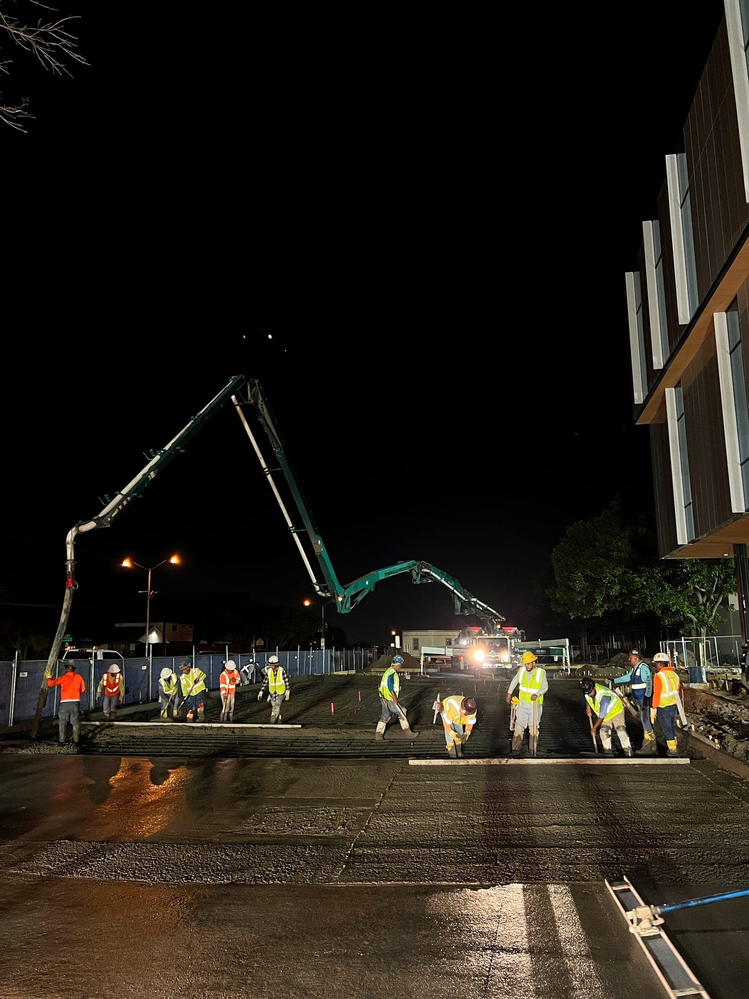 Crew placing and finishing concrete under lights during a night pour