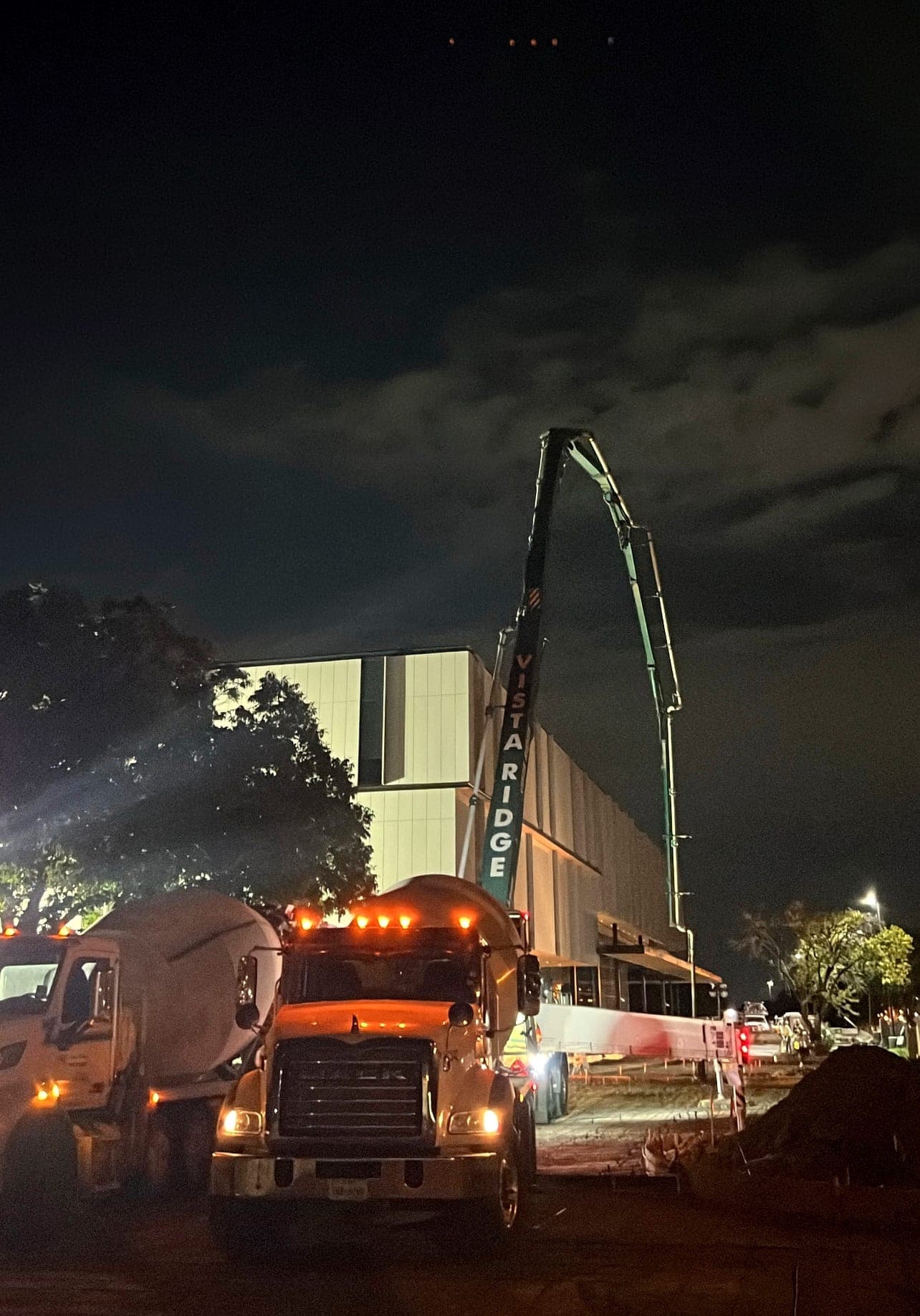 Concrete pump truck and mixer staged for a night pour at a commercial site