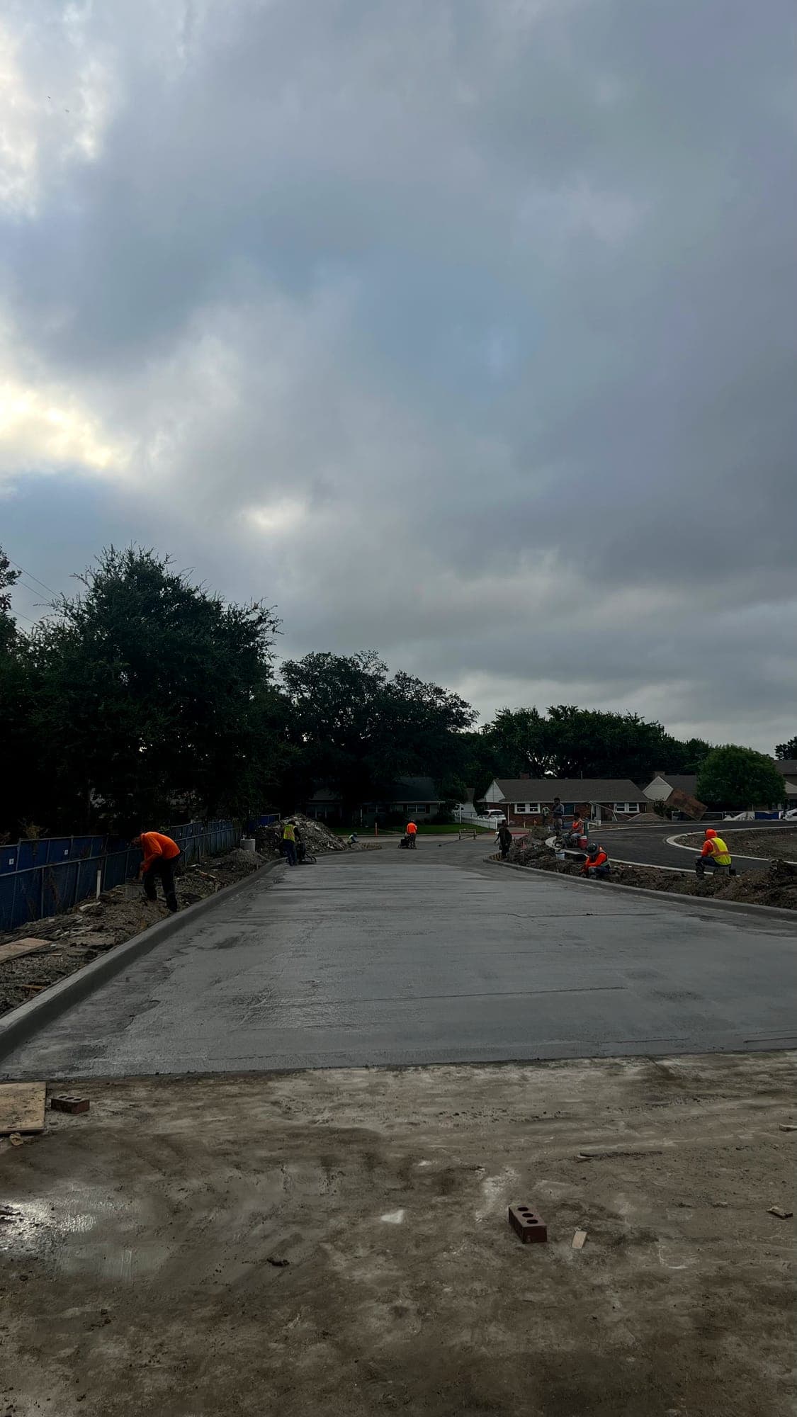 Completed concrete paving section with crew working the next pour