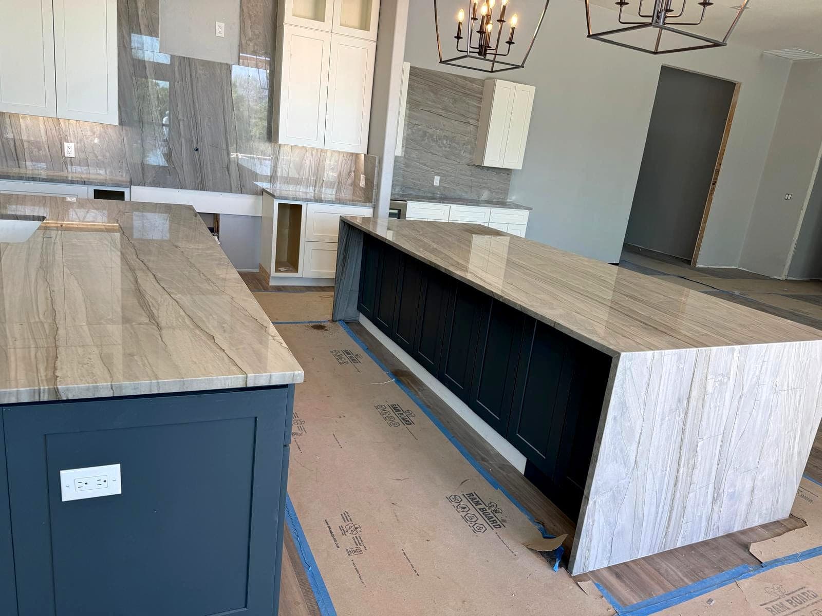 Stone island top and perimeter counters installed over navy cabinetry