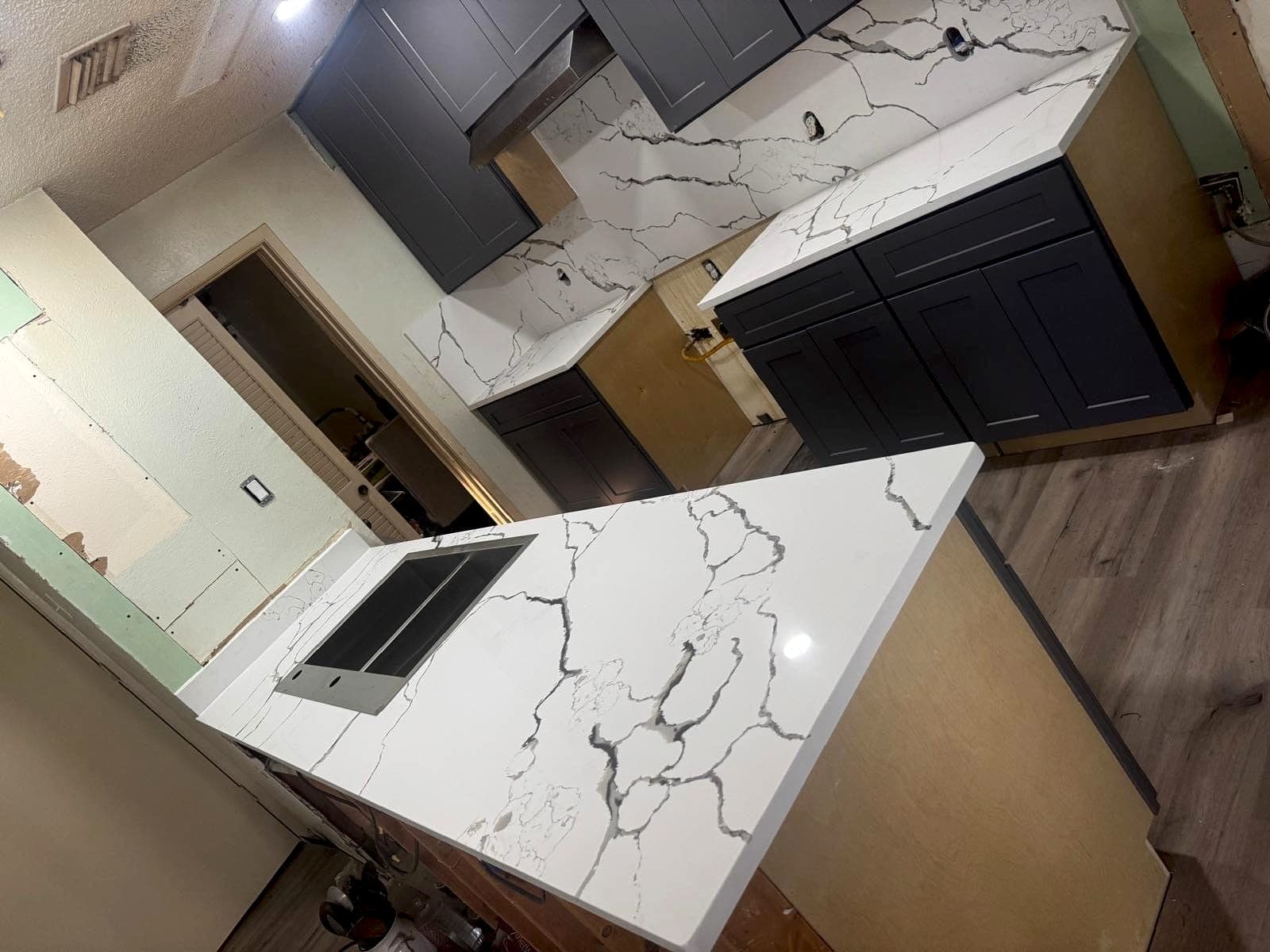 Quartz countertops and waterfall island installed over gray cabinetry