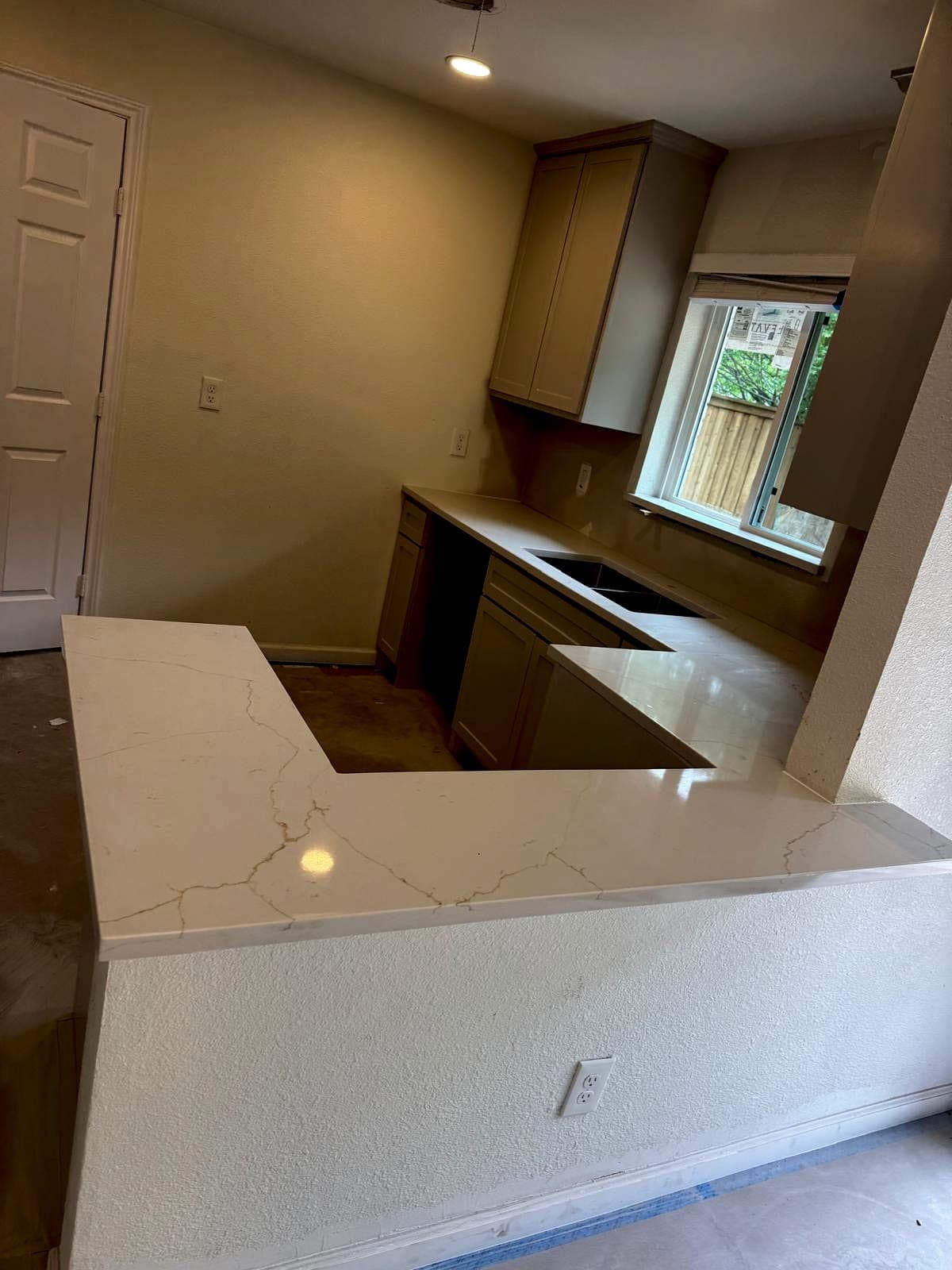 Quartz peninsula with waterfall end panel in a compact kitchen