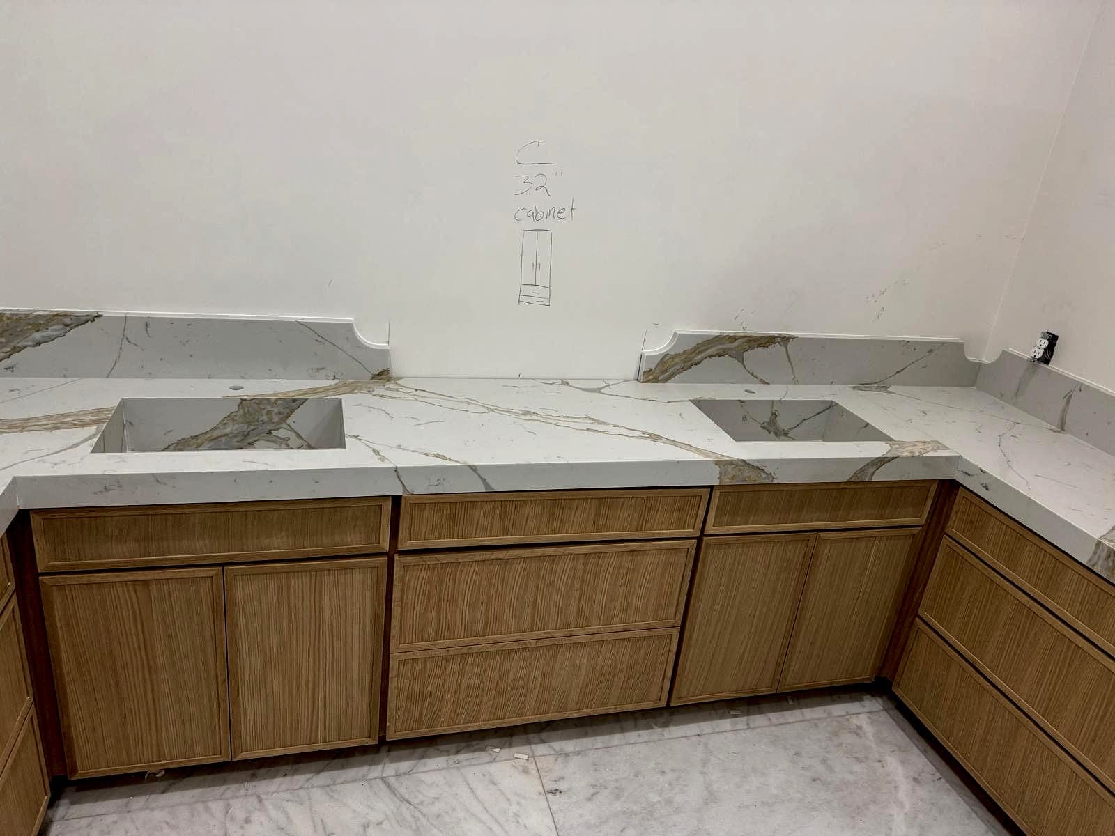 Stone counters with sink and cooktop cutouts installed on white oak cabinetry