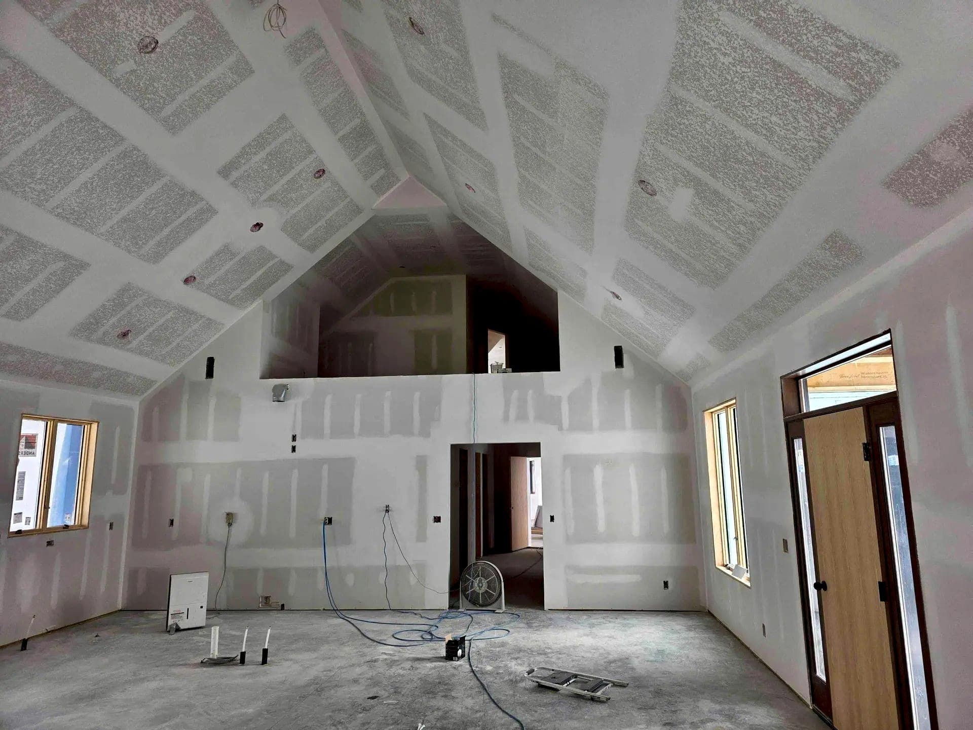 Drywall hung and mudded across a vaulted great room before paint