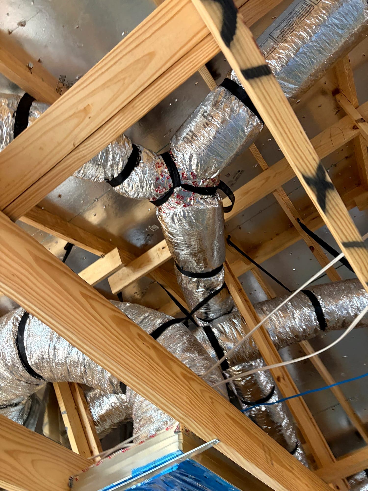Insulated flexible duct runs routed through attic framing