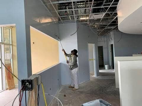 Painter rolling a wall in an open commercial space during buildout
