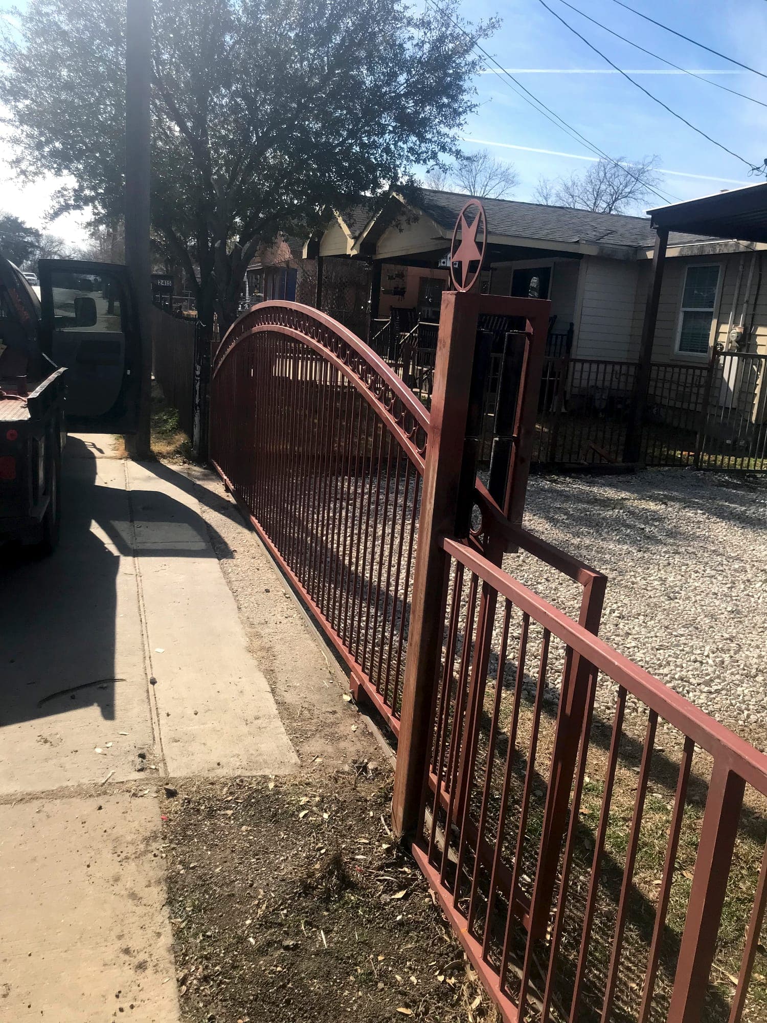 Arched steel gate and matching fence installed at a property entry