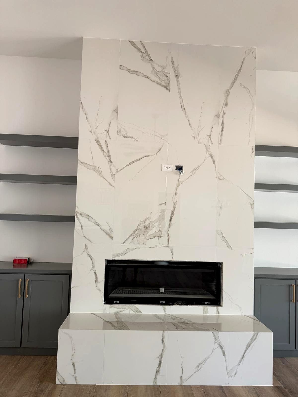 Floor-to-ceiling stone fireplace surround with linear firebox and floating shelves